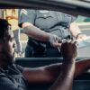 homem recebendo uma multa de trânsito blog mister multas mão policial segurando a prancheta com a multa